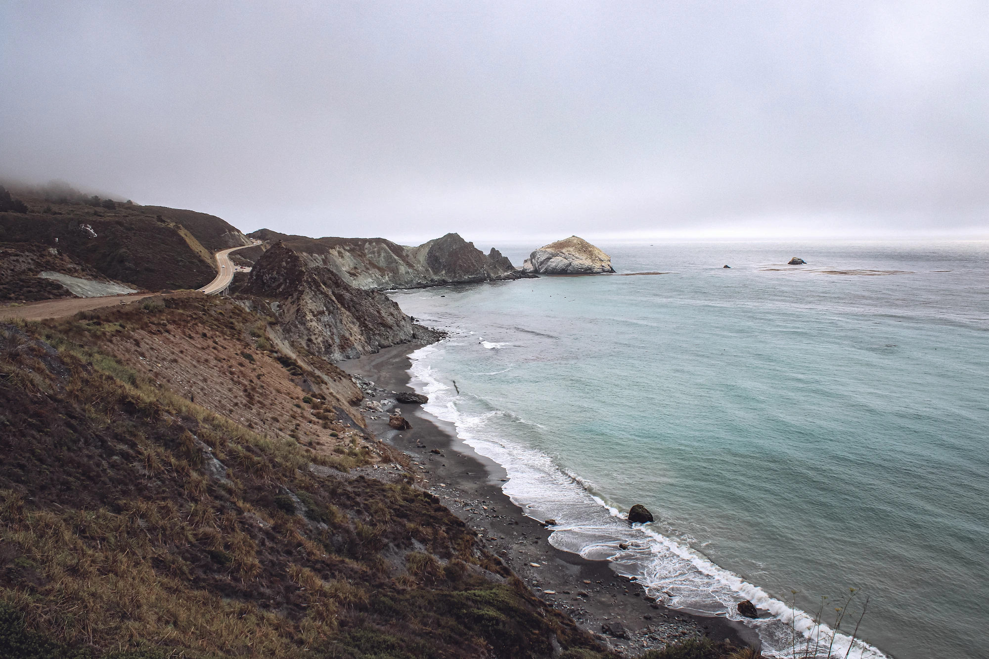 The California coastline along Highway 1, green bluffs meeting the Pacific.