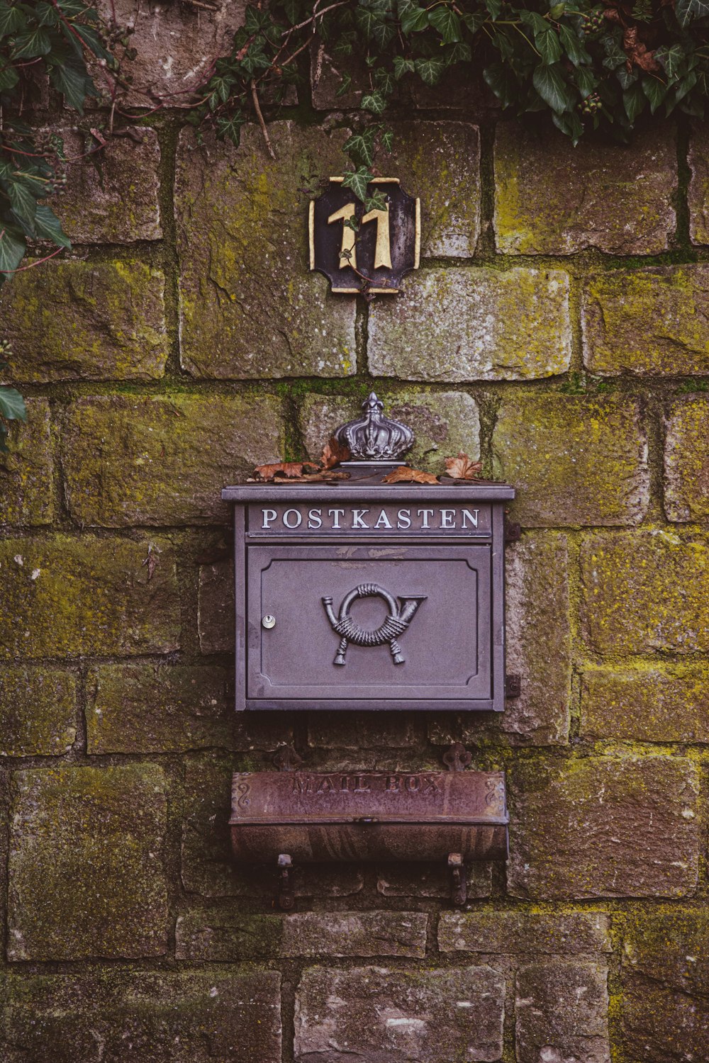 a mailbox on a brick wall with ivy growing over it