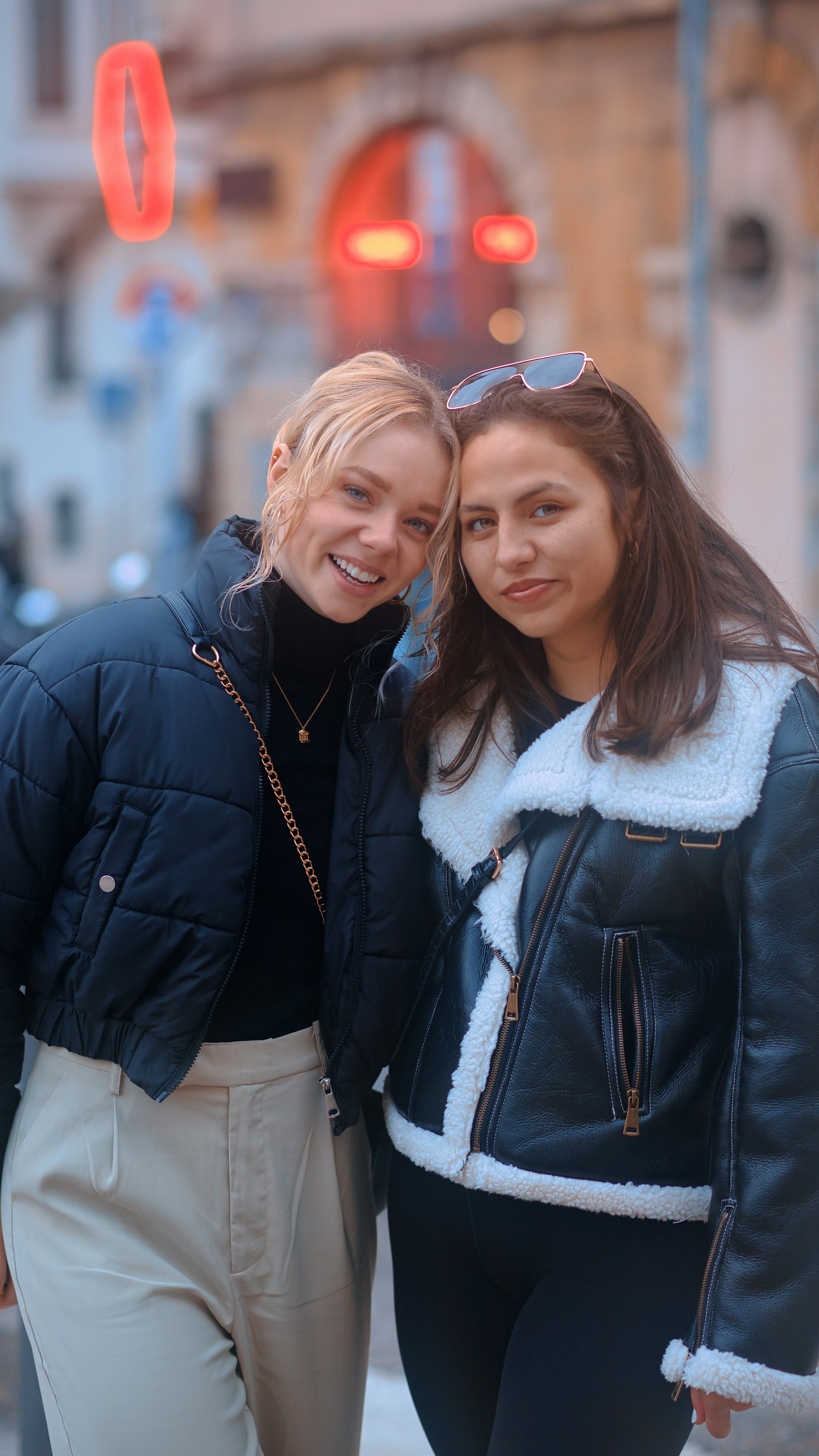 two women standing next to each other in front of a building