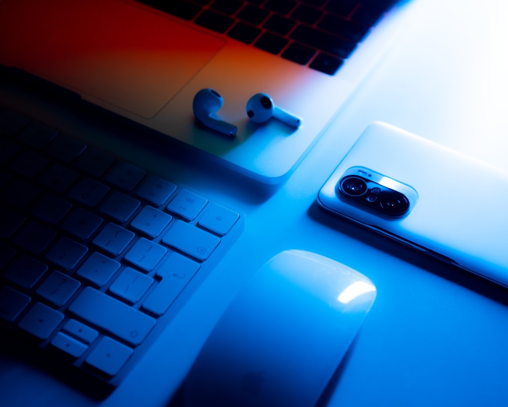 a computer keyboard, mouse, and cell phone on a desk