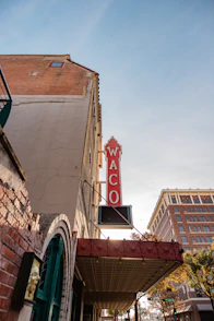 a red neon sign hanging from the side of a building