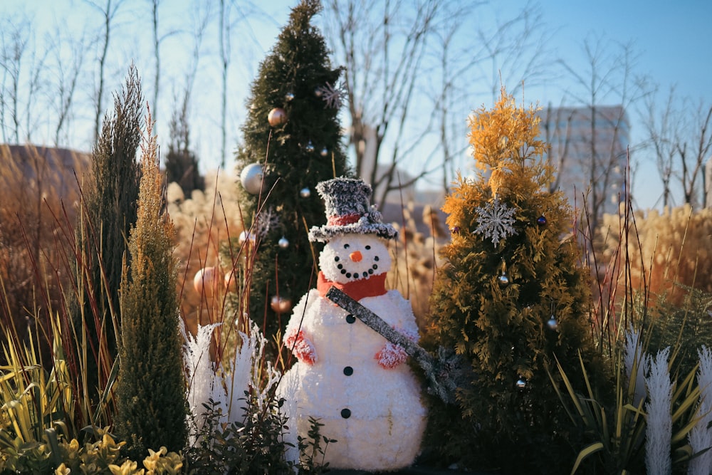 a snowman in a garden with a christmas tree in the background