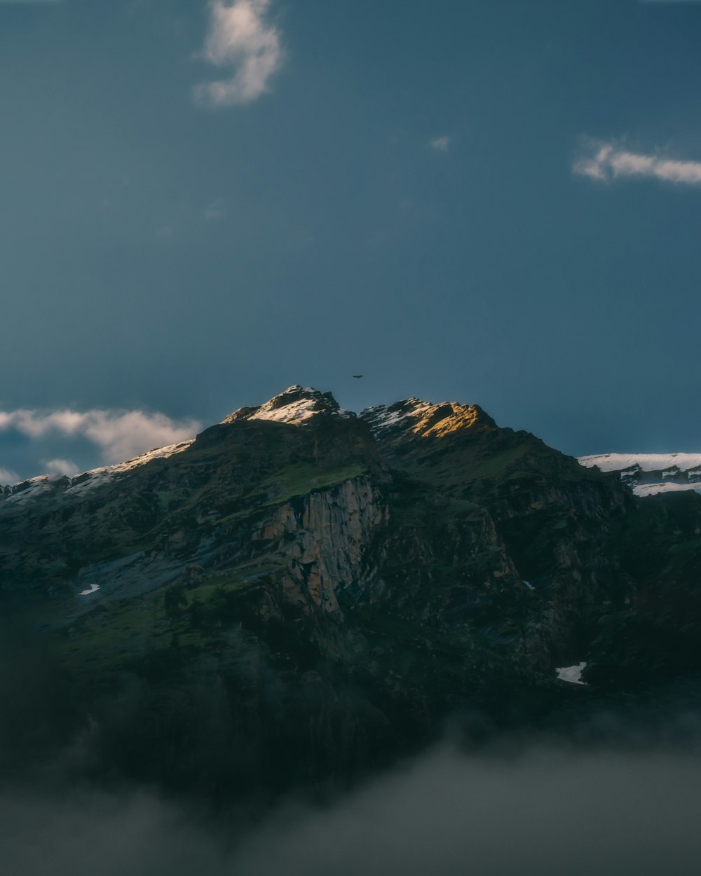 a very tall mountain covered in snow under a cloudy sky