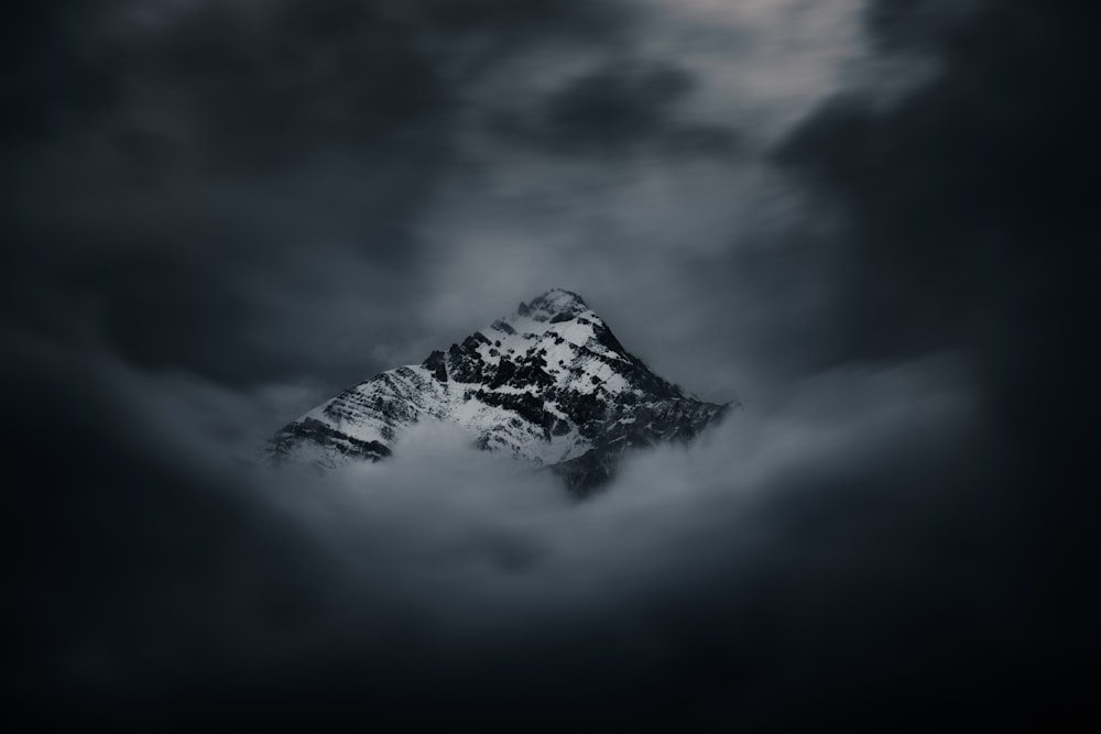 a mountain covered in clouds under a cloudy sky