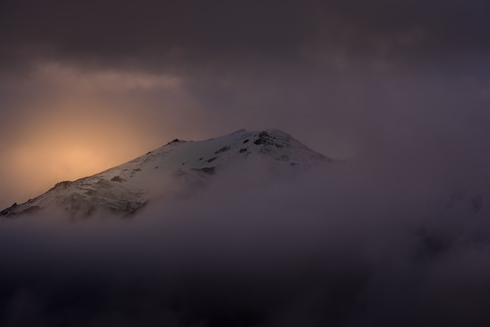 a snow covered mountain under a cloudy sky