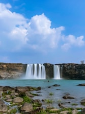 a large waterfall with a man in a boat in the water