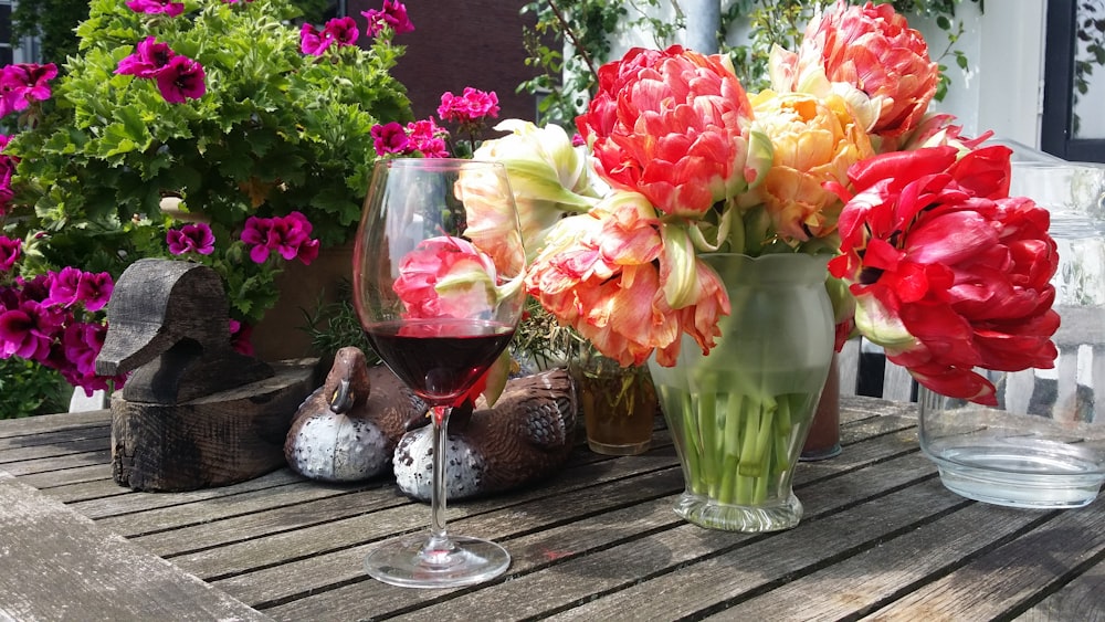 a glass of wine and some flowers on a table