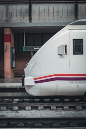 a white bullet train parked at a train station