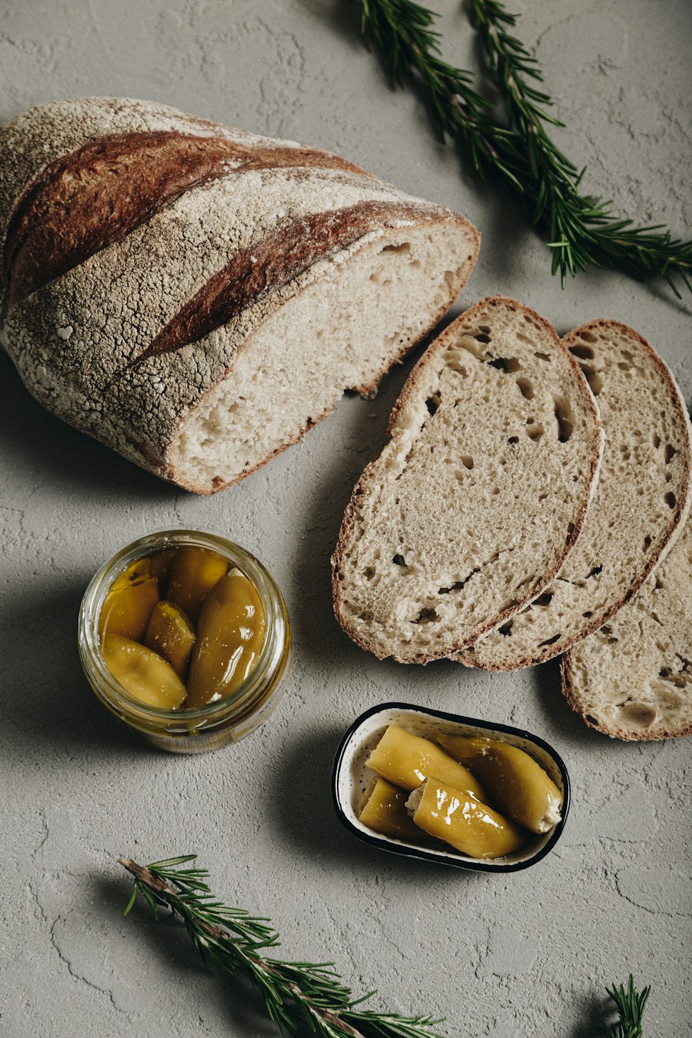 a loaf of bread with olives and a jar of pickles