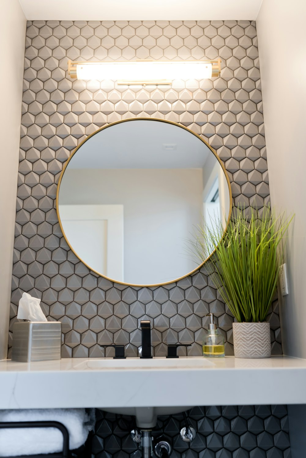 a bathroom sink with a round mirror above it