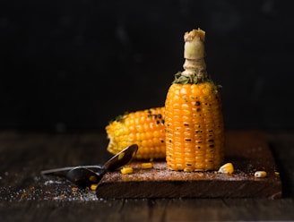 Grilled corn on the cob with char marks, sprinkled with herbs and butter melting.