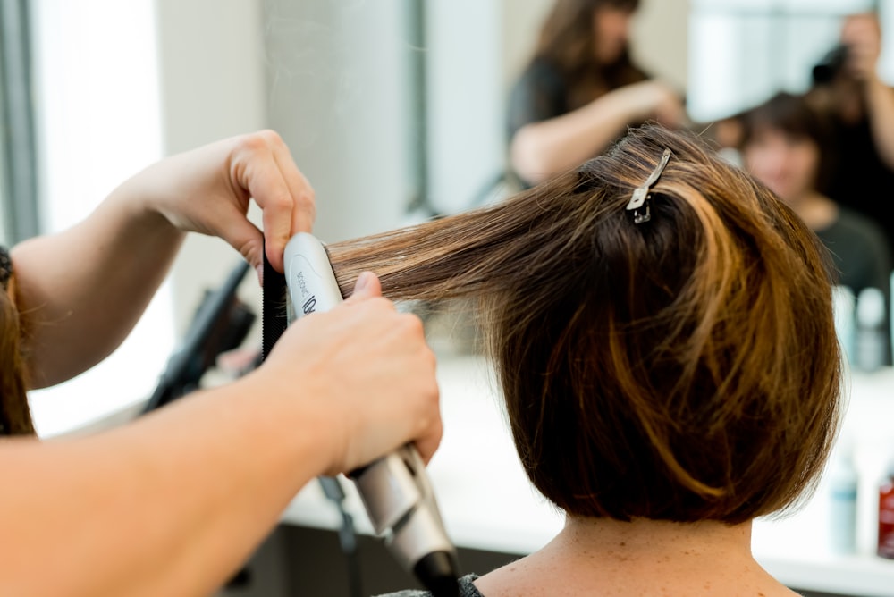 a woman blow drying her hair in a salon