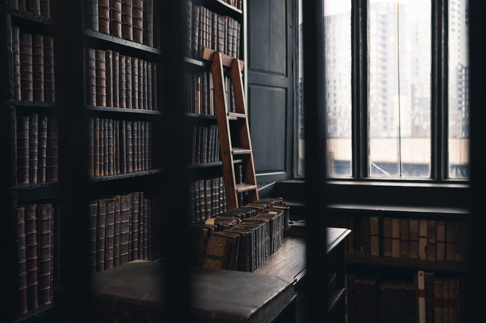 a bookshelf filled with lots of books next to a window