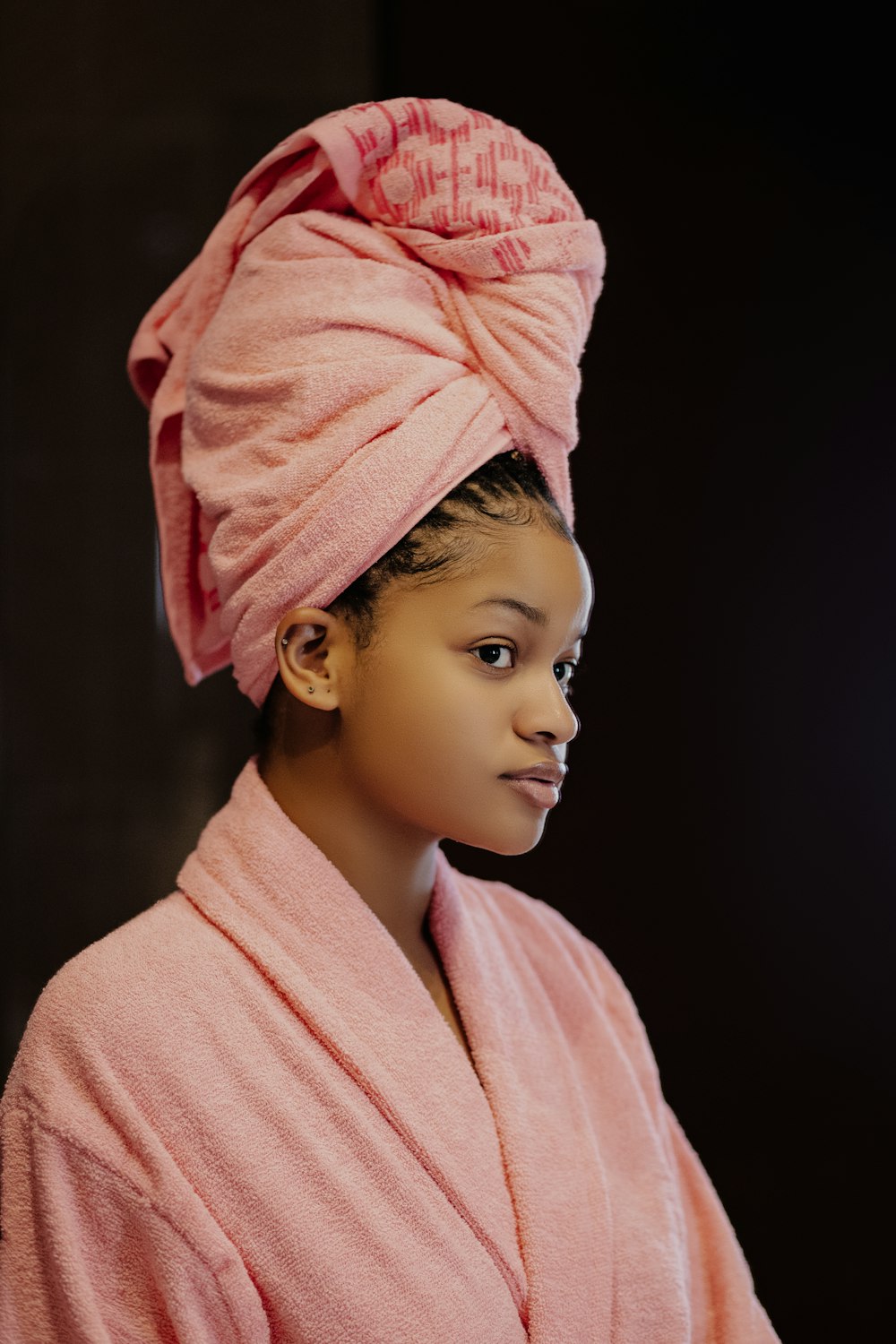 a young girl wearing a pink robe and a pink towel