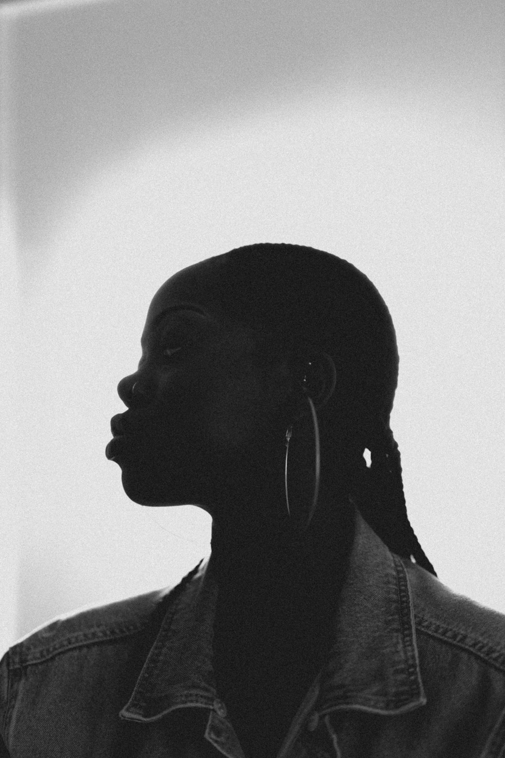 a woman in a denim jacket and earrings