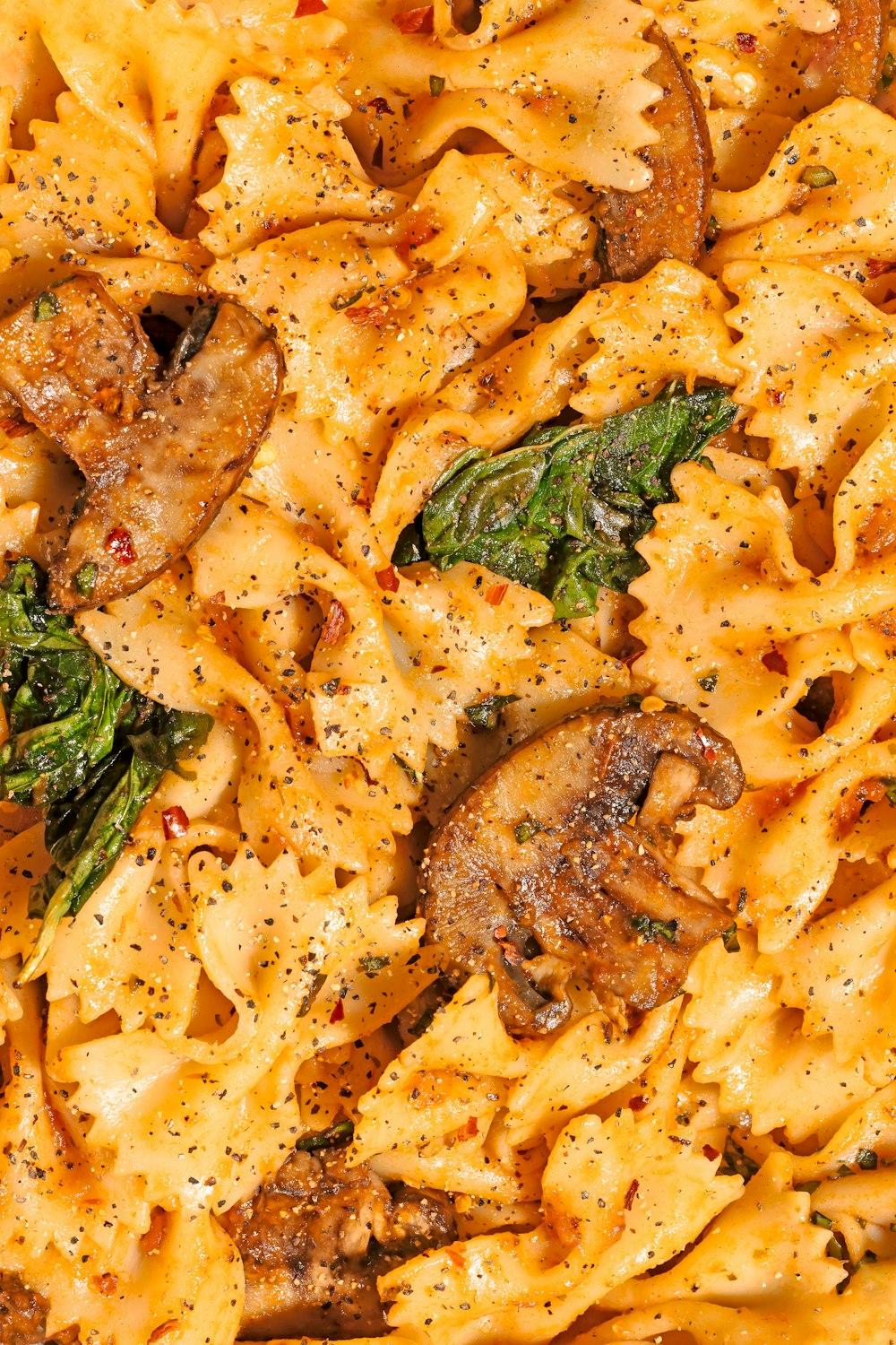 a close up of a pasta dish with mushrooms and spinach