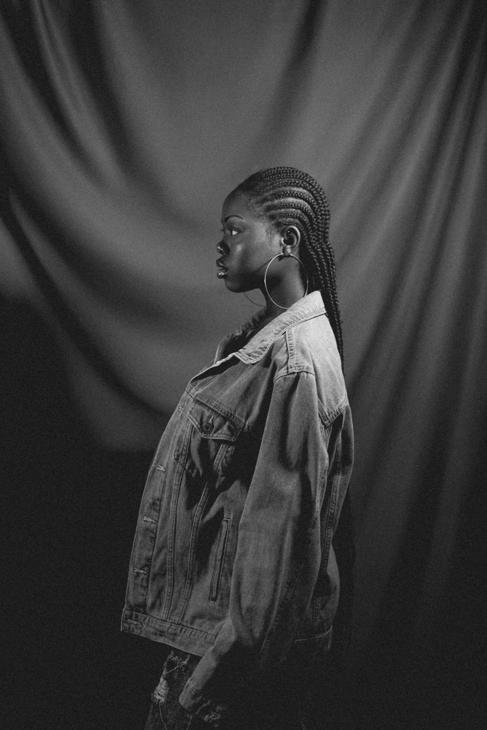 a woman with braids standing in front of a curtain