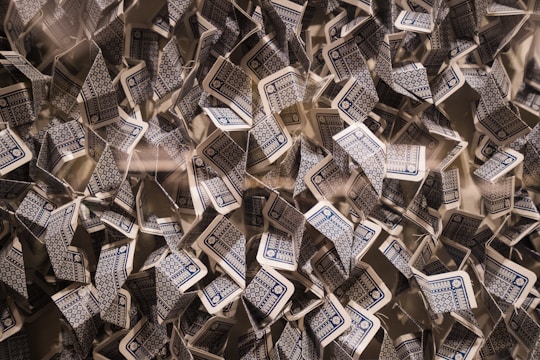 A chaotic arrangement of playing cards with blue and white patterned backs in various orientations, creating a dynamic and intricate visual effect.