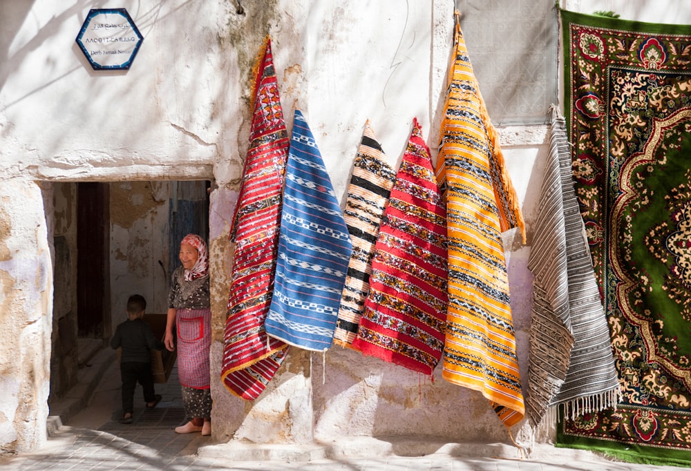 a woman standing in a doorway between colorful rugs