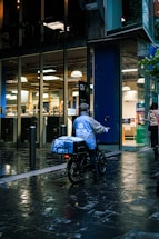 A friendly delivery rider handing over groceries at night outside a Manchester apartment.