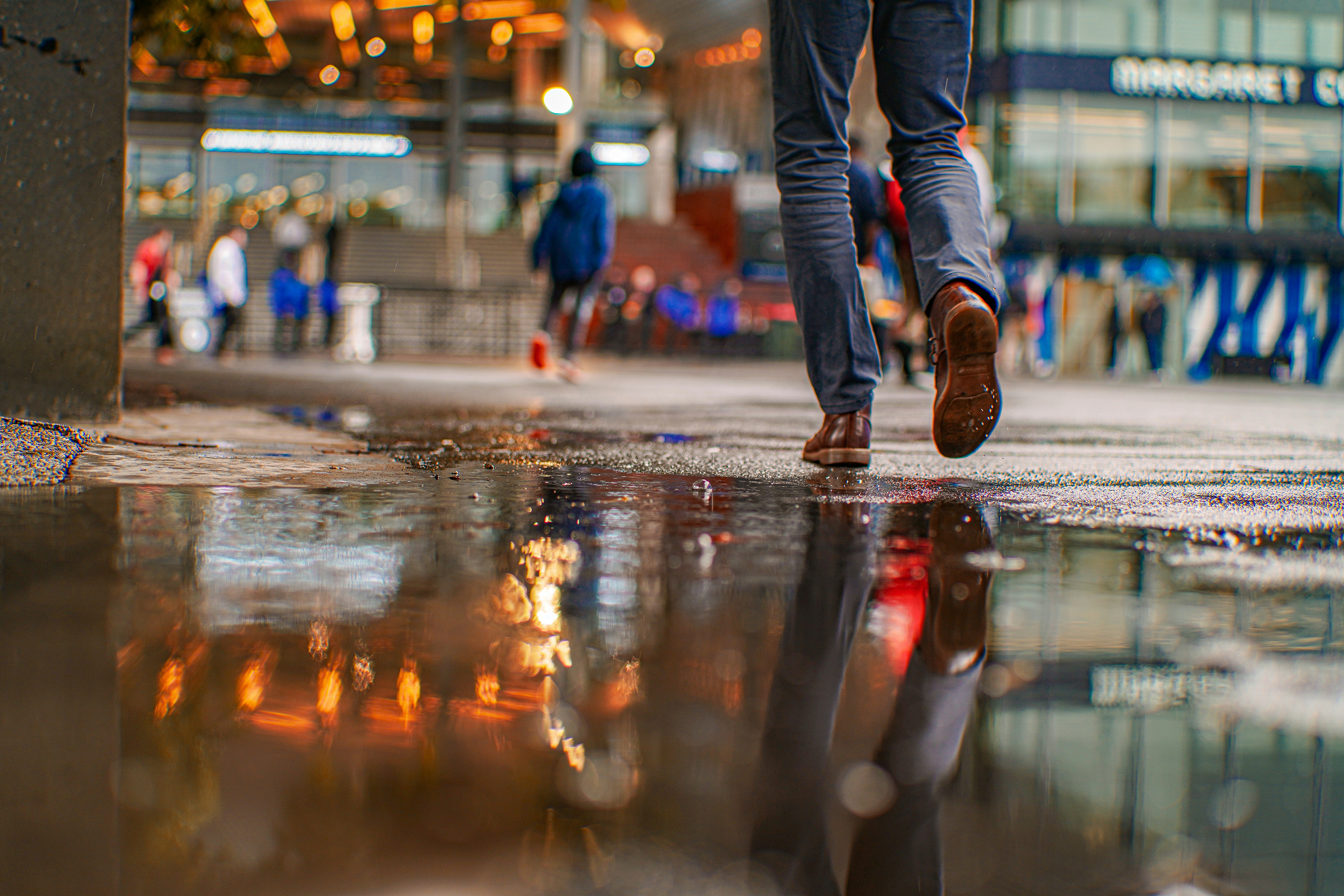 a man walking down a street next to a puddle
