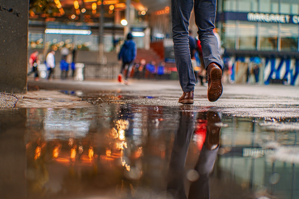 a man walking down a street next to a puddle