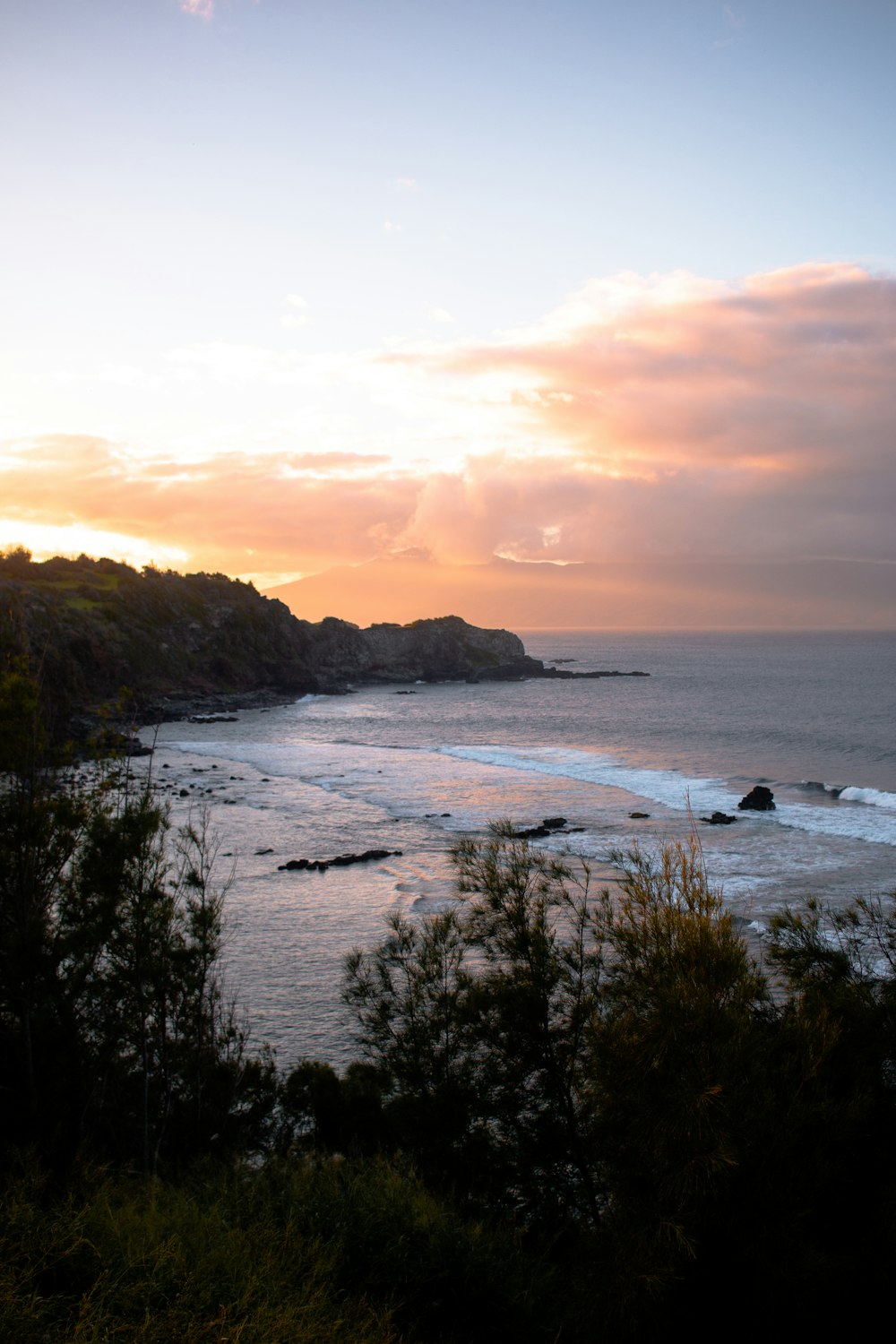 the sun is setting over the ocean and a beach