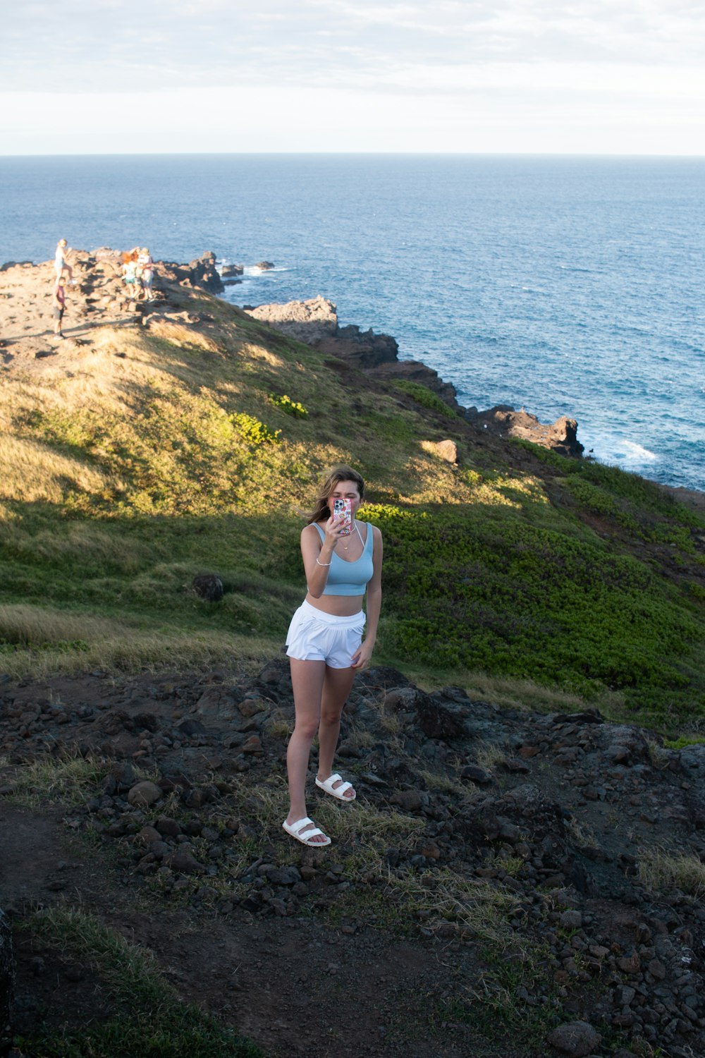 a woman standing on a rocky cliff by the ocean