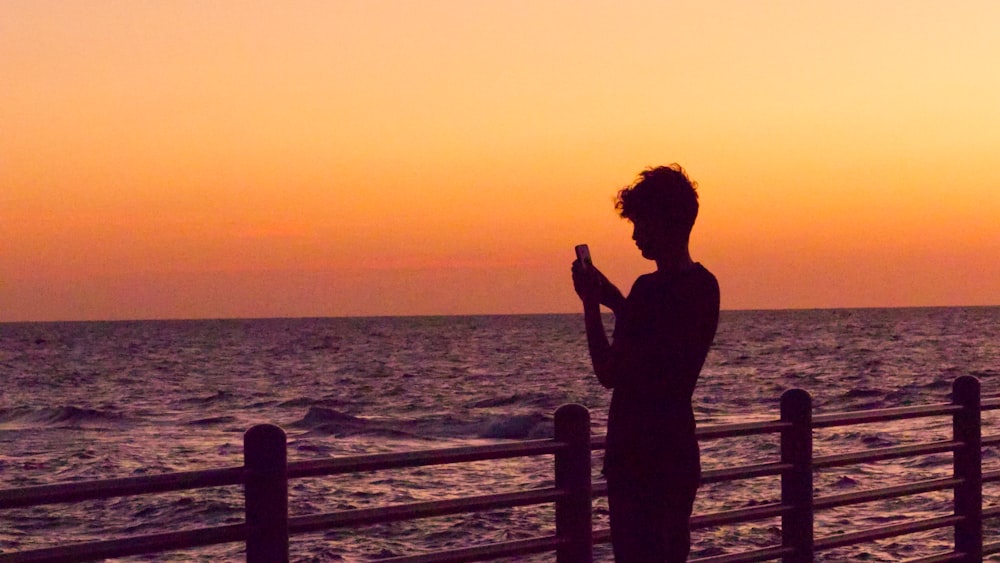 a man standing on a pier next to the ocean