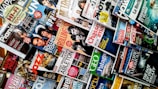 A variety of magazines are displayed in a chaotic but organized manner, featuring popular titles with colorful covers. The magazines are stacked and overlapping, showcasing diverse topics like music, science, travel, and lifestyle.