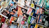 A variety of magazines are displayed in a chaotic but organized manner, featuring popular titles with colorful covers. The magazines are stacked and overlapping, showcasing diverse topics like music, science, travel, and lifestyle.