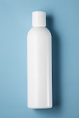 A plain white plastic bottle with a cylindrical shape and a cap on top, positioned vertically against a light blue background.