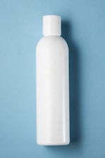 A plain white plastic bottle with a cylindrical shape and a cap on top, positioned vertically against a light blue background.