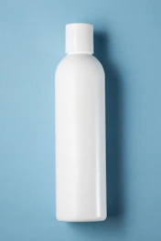 Close-up of clear pharmaceutical-grade plastic bottle scalps on a clean white surface.