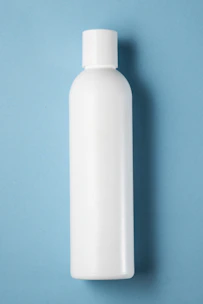 Close-up of clear pharmaceutical-grade plastic bottle scalps on a clean white surface.