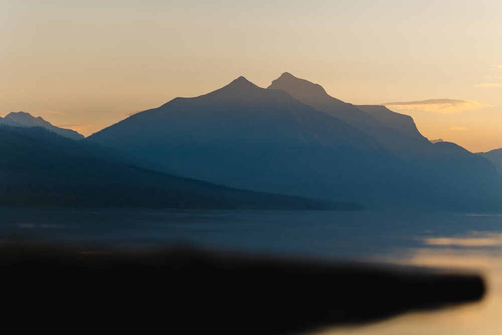 a lake with mountains in the background at sunset