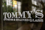 a close up of a glass door with the name tommy's antiques and stained
