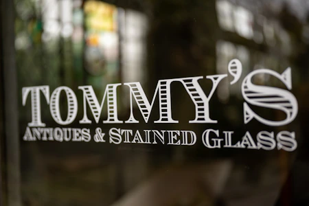 a close up of a glass door with the name tommy's antiques and stained