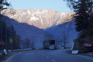 a truck driving down a road with a mountain in the background