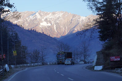 a truck driving down a road with a mountain in the background