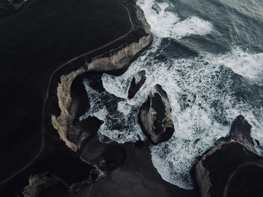 an aerial view of the ocean and rocks