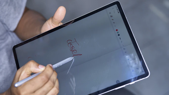 A close-up of a hand filling out a digital form on a tablet.