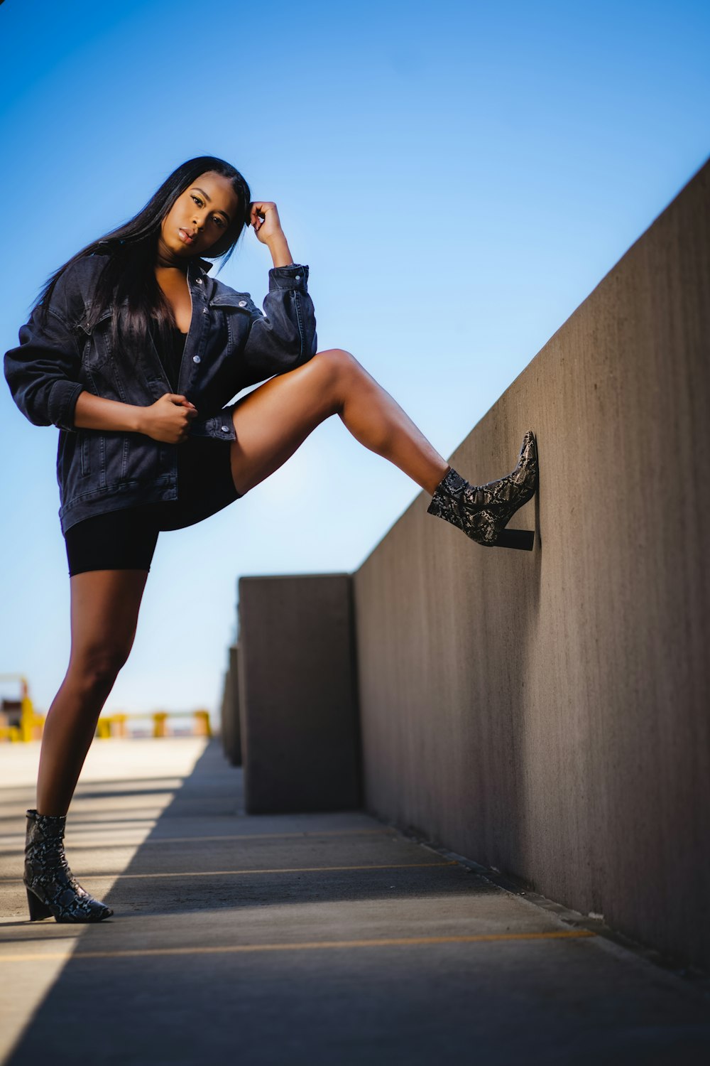a woman leaning against a wall while wearing high heels