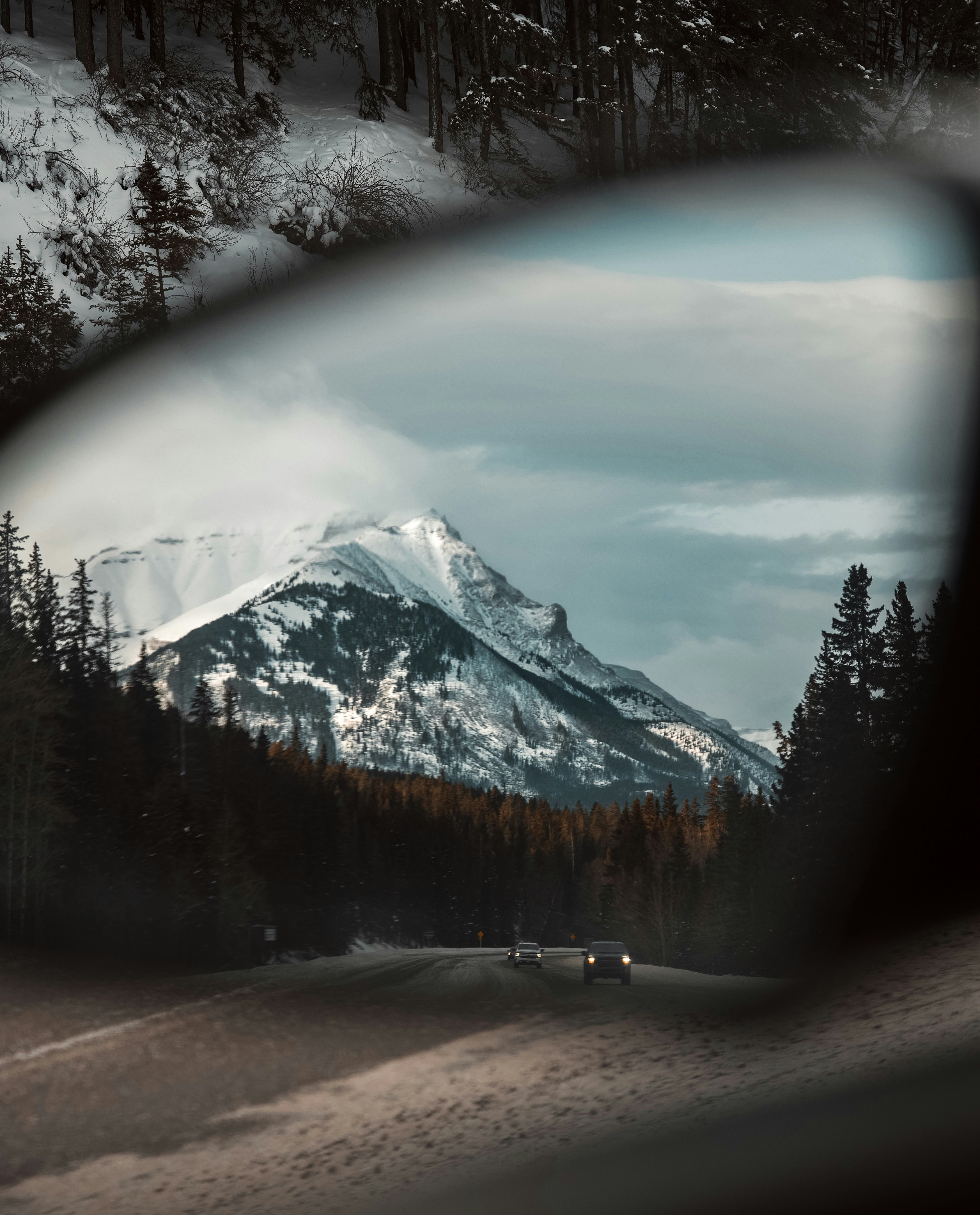 a car's side view mirror with a mountain in the background