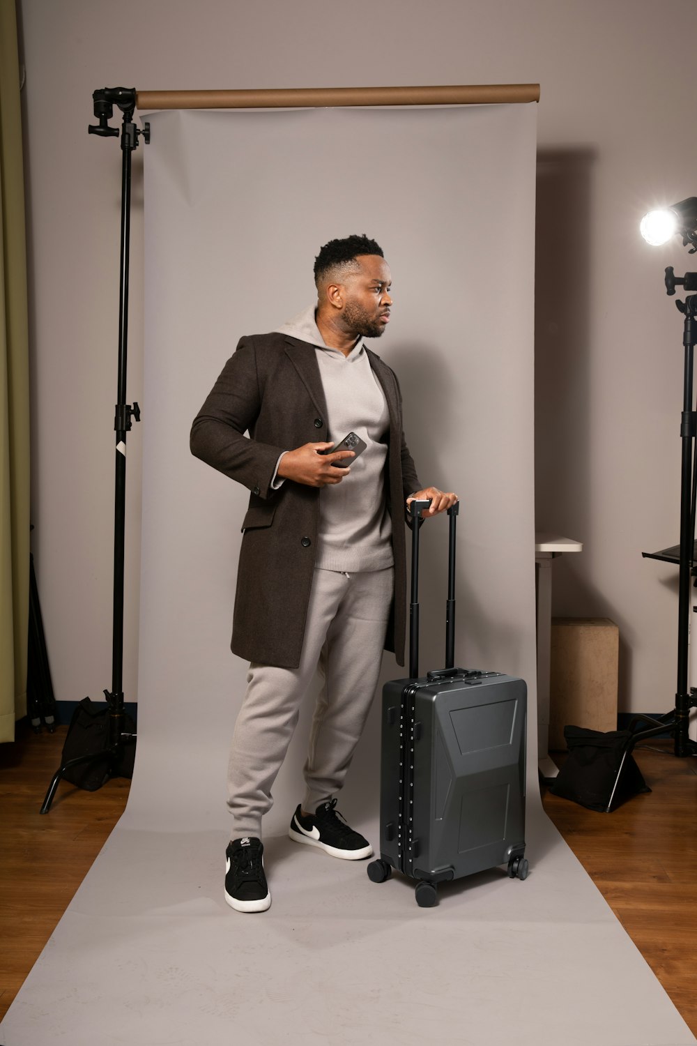 a man standing next to a suitcase in a photo studio