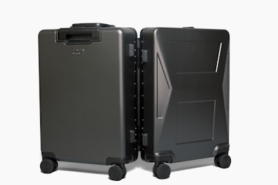 A compact carry-on suitcase with four spinner wheels next to a travel backpack.