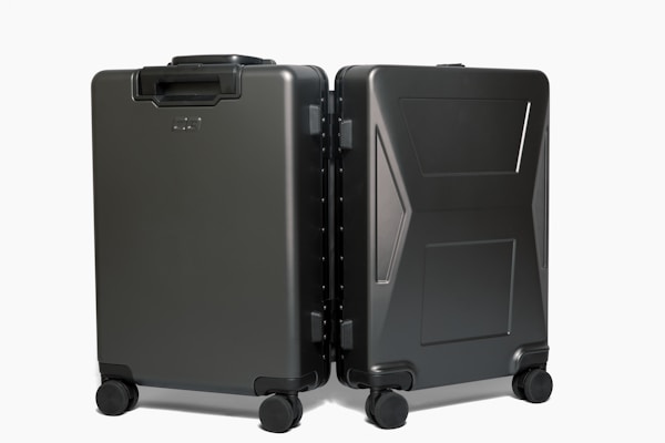 Two sleek, black hard-shell suitcases positioned side by side on four wheels each, showcasing modern design and durability with a smooth matte finish.