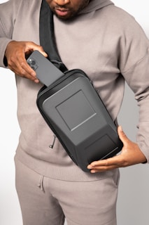 a man in a gray sweater is holding a black case