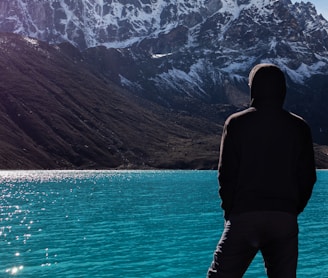 a man standing on the edge of a cliff overlooking a lake