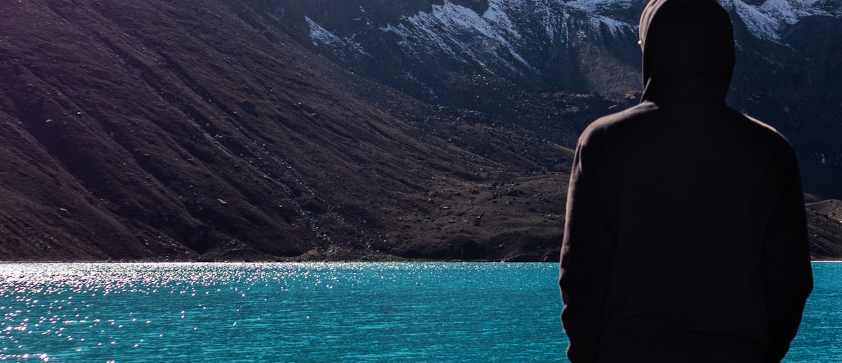 a man standing on the edge of a cliff overlooking a lake